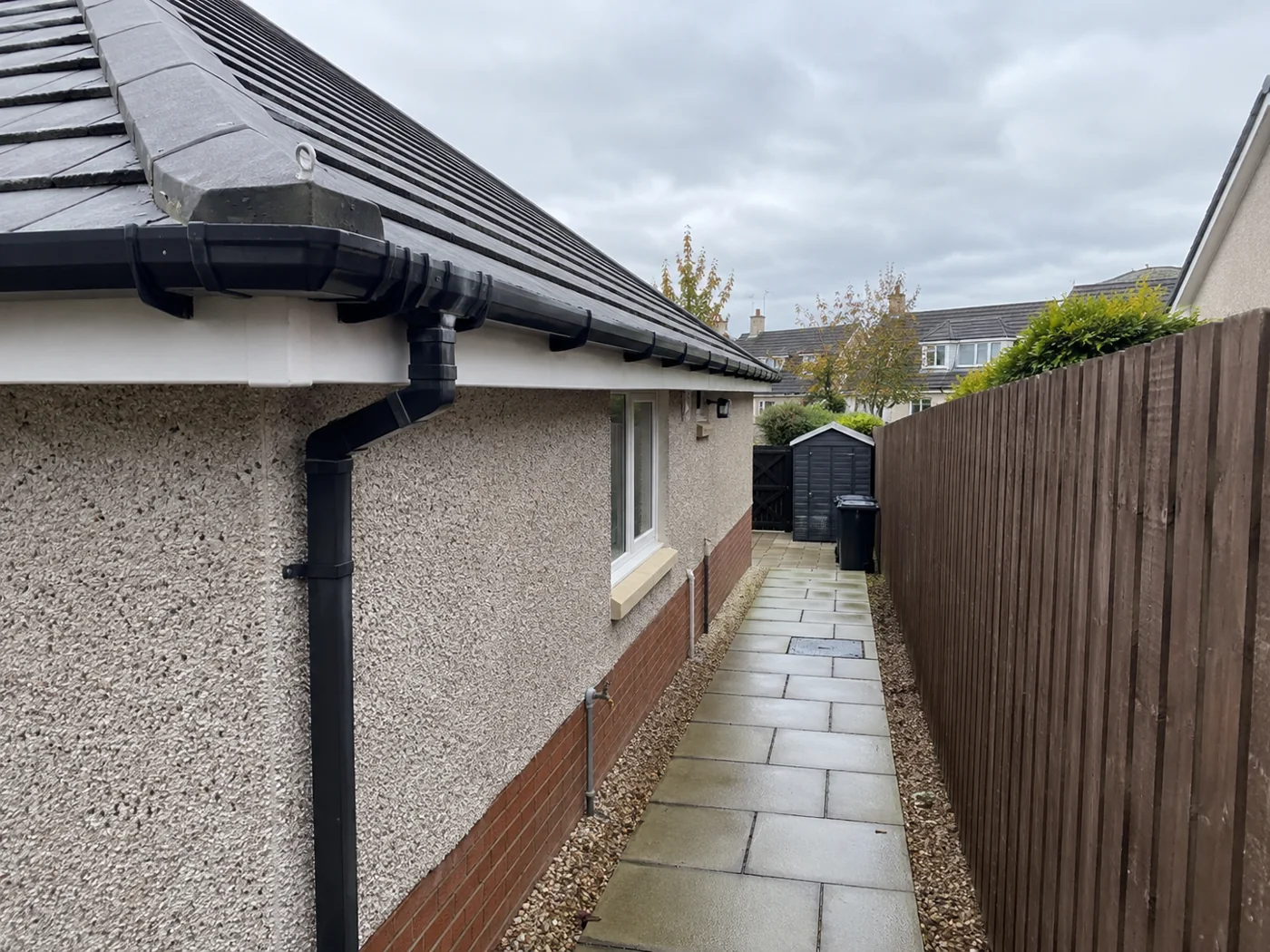 Paved side path beside a house with roof eaves above